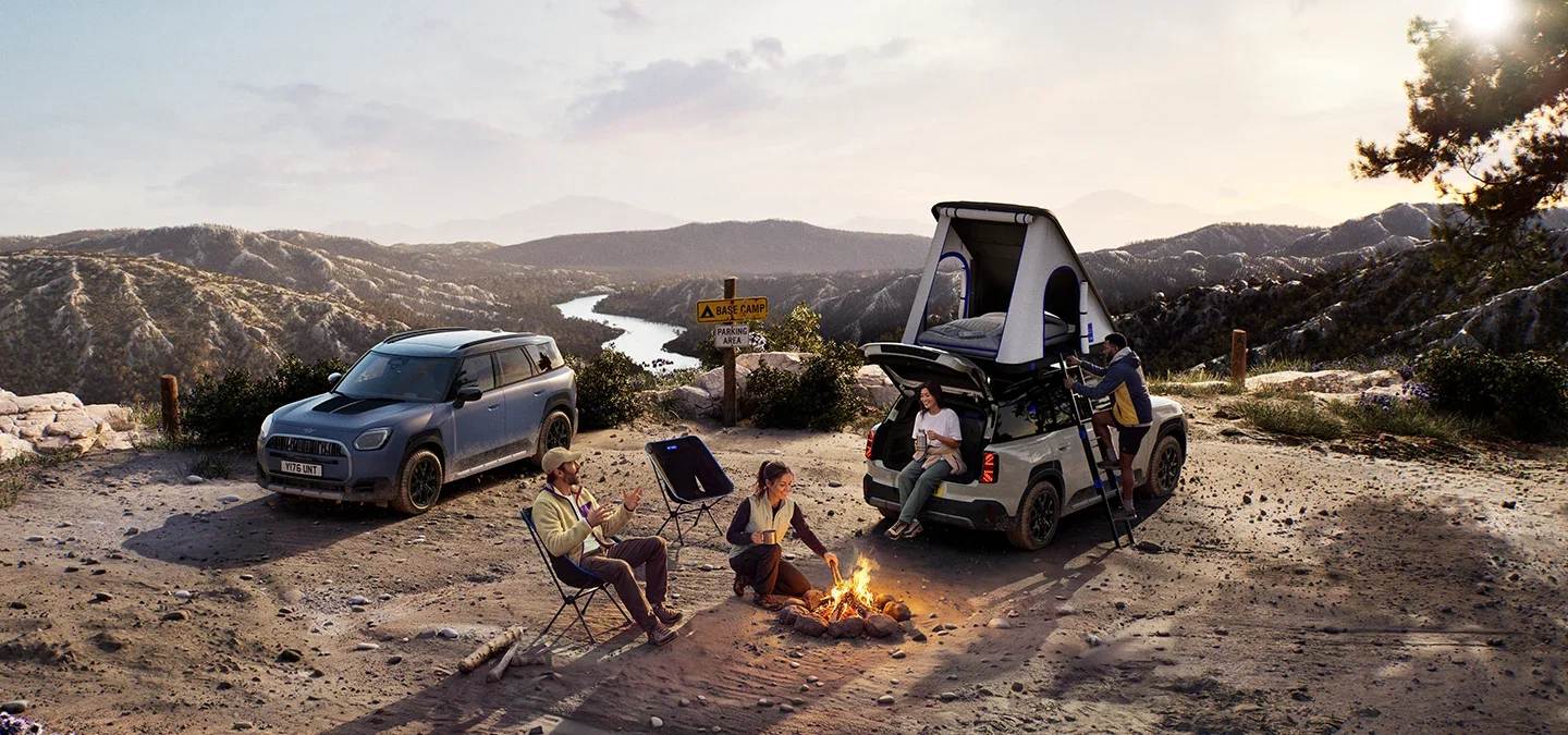 Two MINI Countryman vehicles at a mountain campsite.