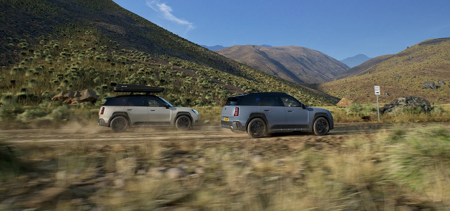 Two MINI Countryman vehicles driving across mountain terrain.