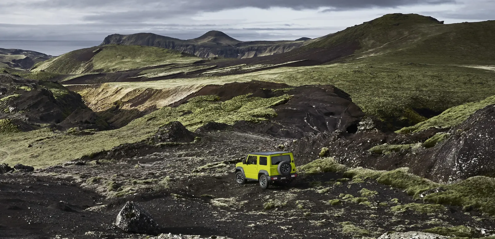 Black Suzuki Jimny cruising on a winding road