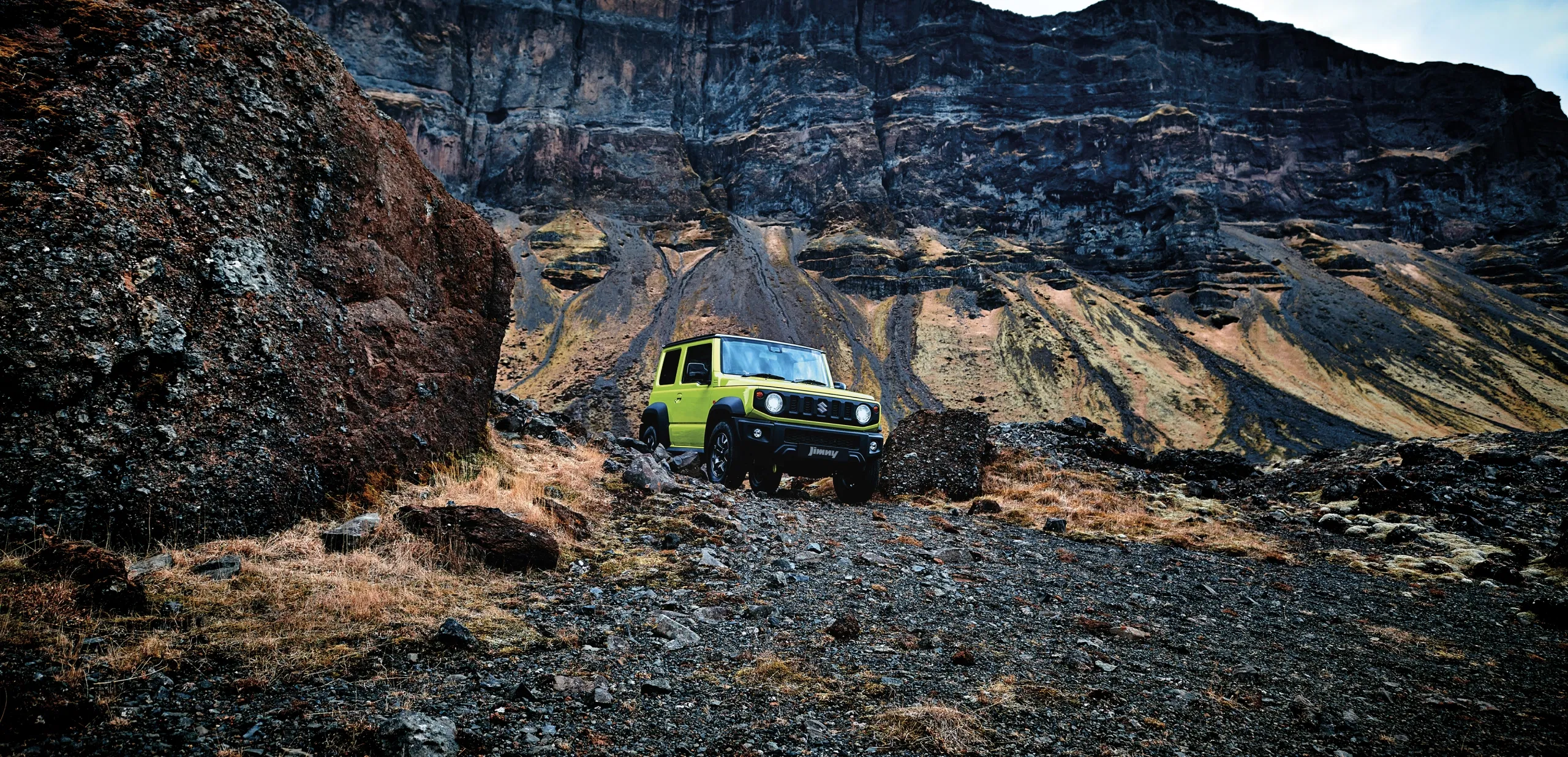 Green Suzuki Jimny parked on rocky ground