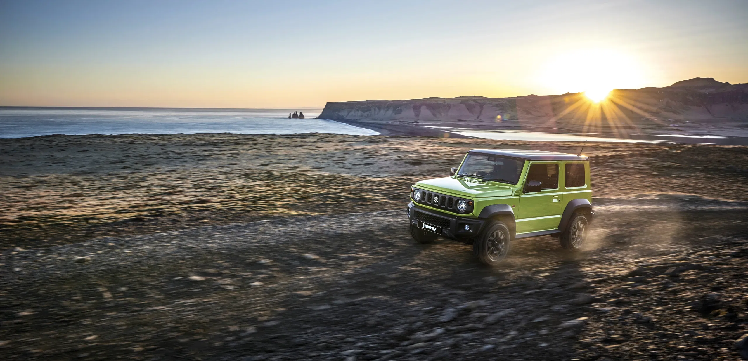 Suzuki Jimny parked near the ocean at sunset