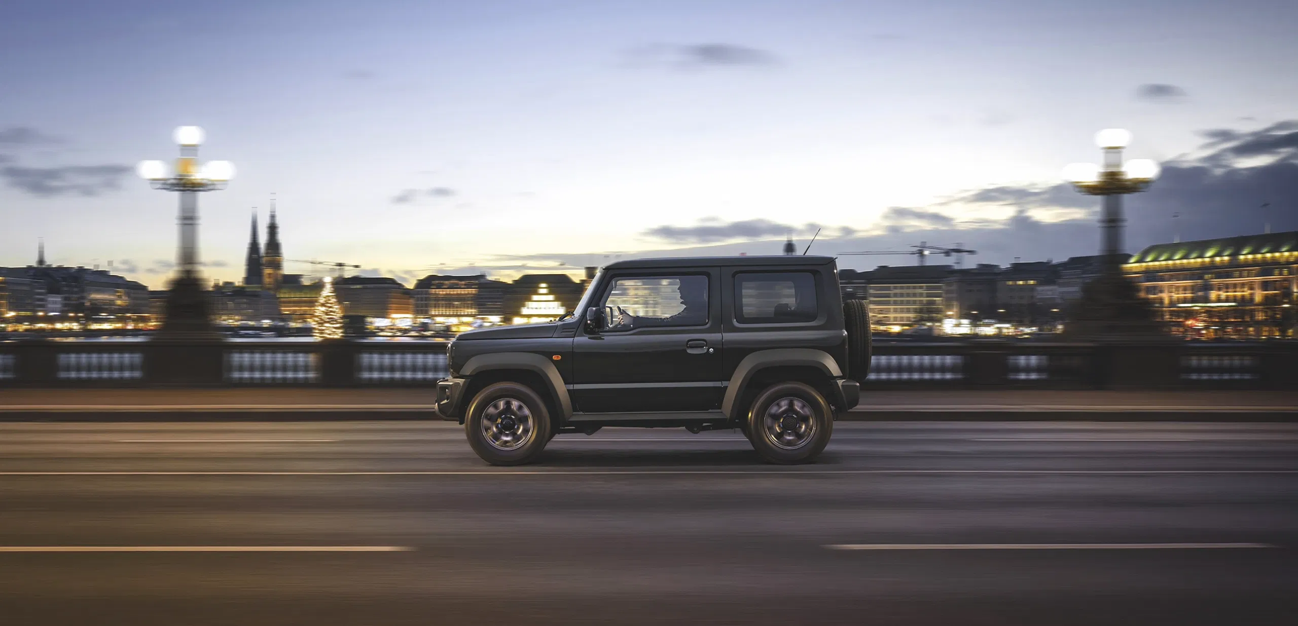 Black Suzuki Jimny cruising on a winding road