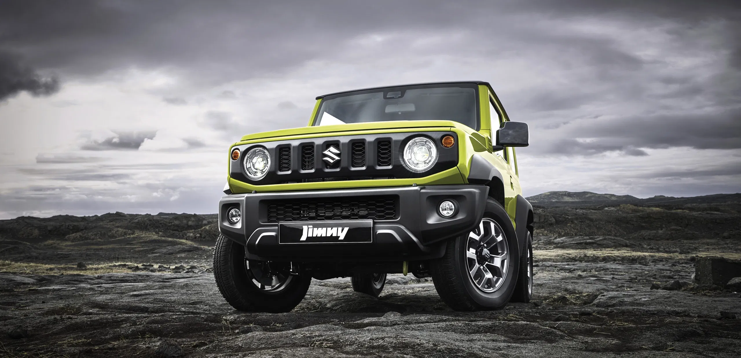 Suzuki Jimny parked on rugged rocks during sunset