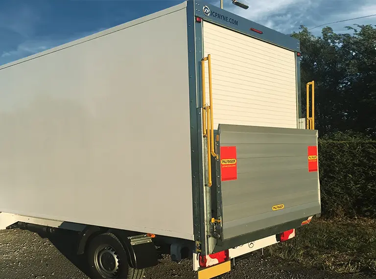 A Palfinger vertical tail lift lowered behind a box body, ready for loading.